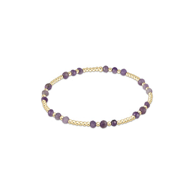 Bracelet with purple beads on a gold band against a white background
