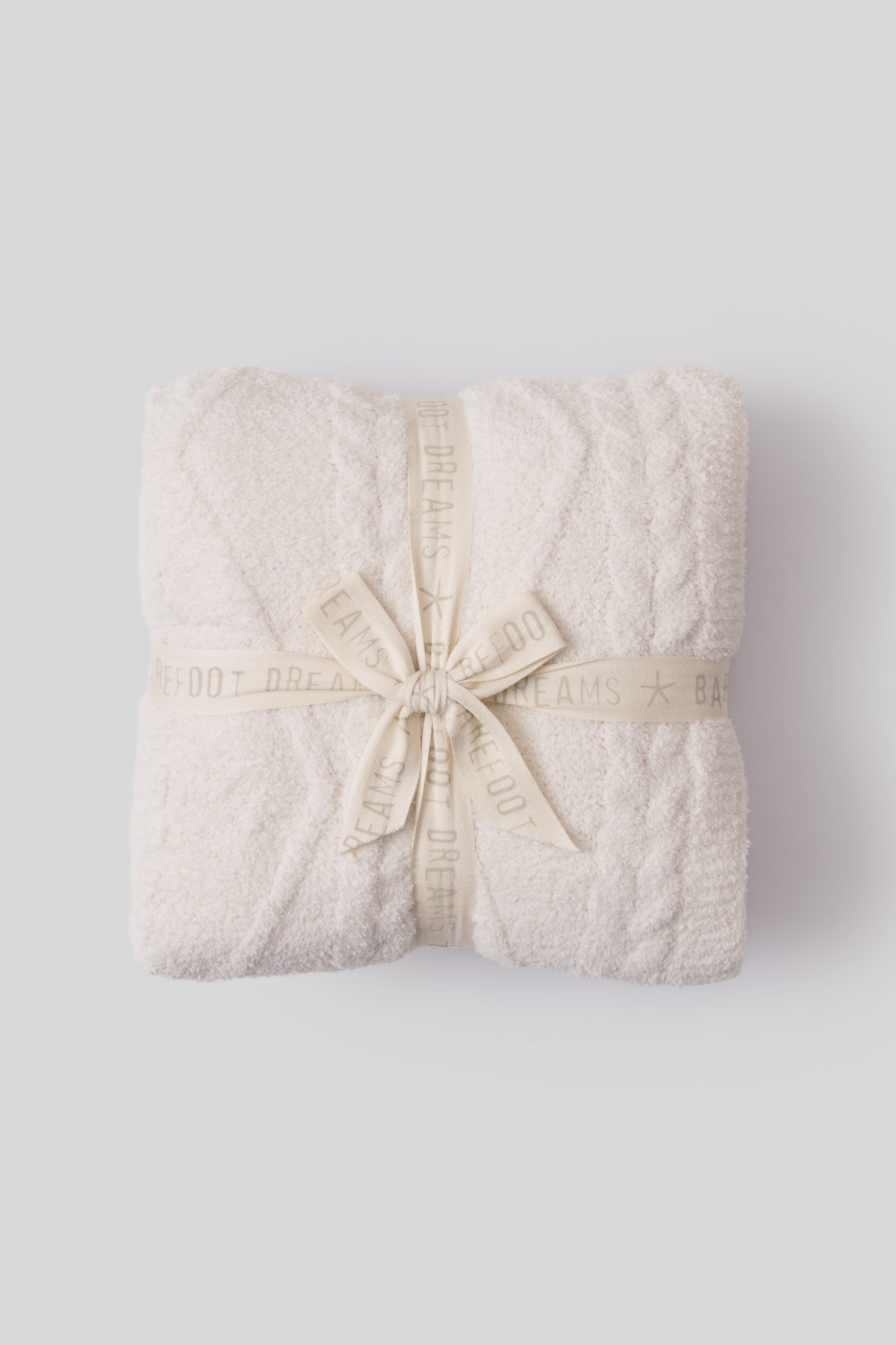 Folded beige blanket with a ribbon on a light gray background