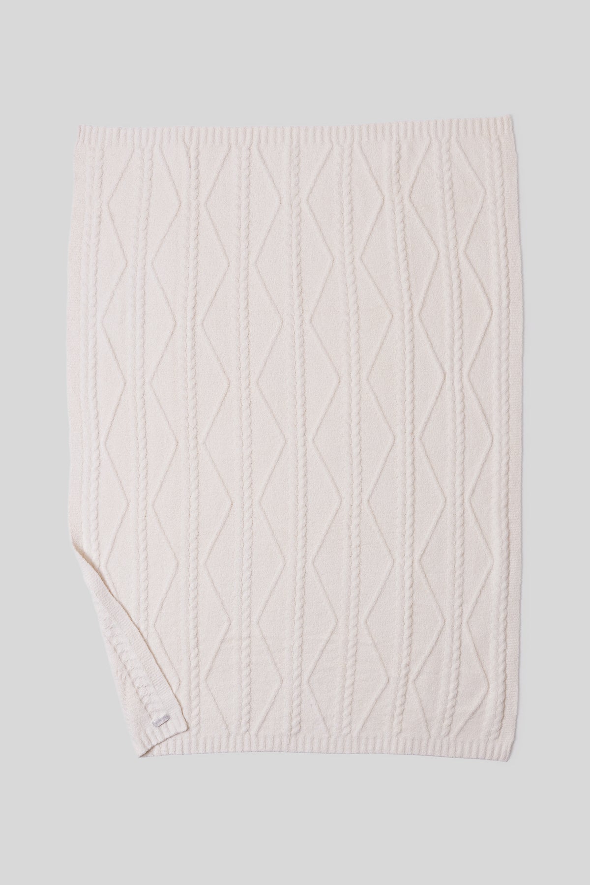 cream cable knit blanket on a light gray background