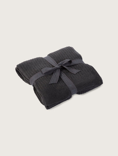 Folded dark gray blanket tied with a ribbon on a light beige background