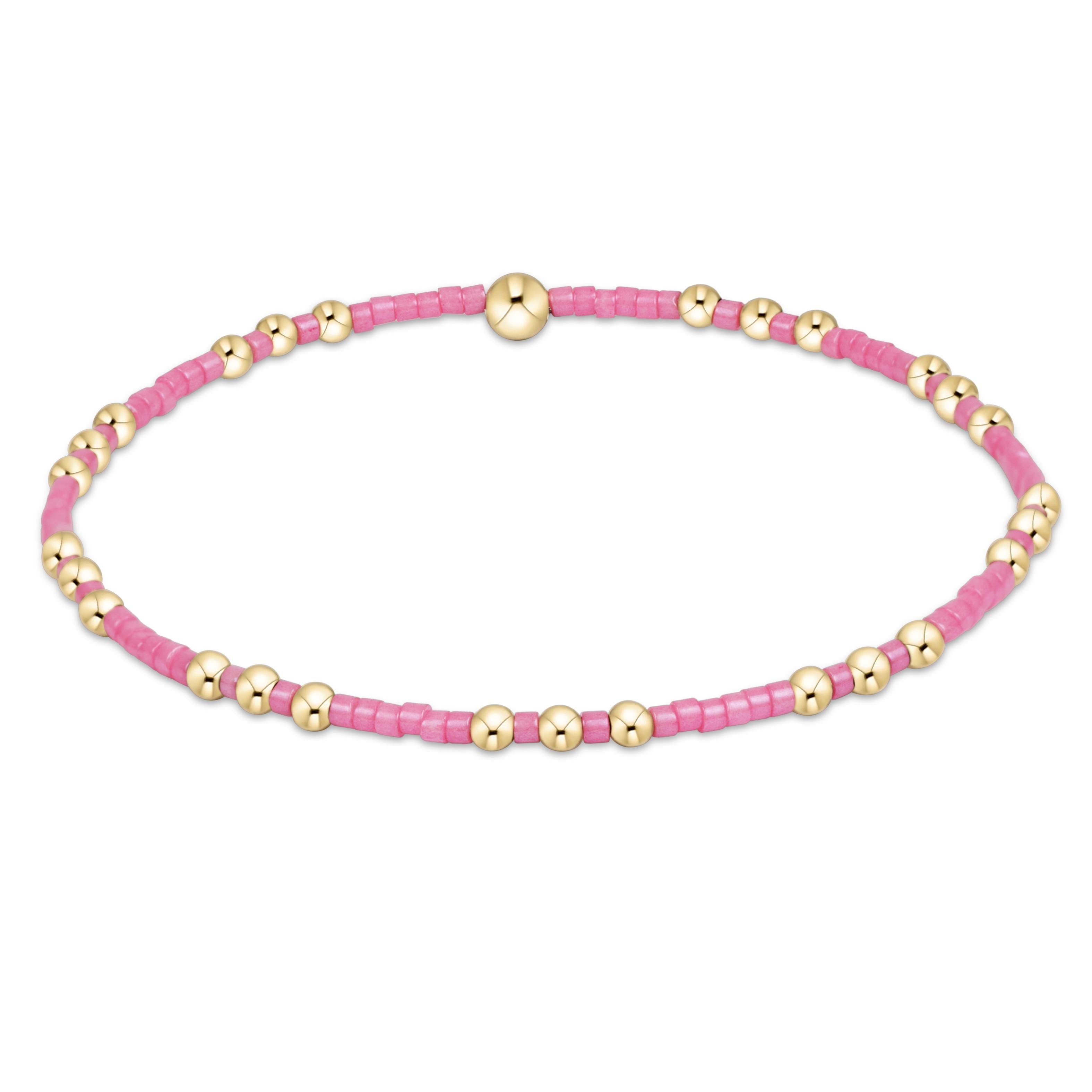 Pink beaded bracelet with gold beads on a white background