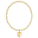 Gold beaded bracelet with a heart-shaped pendant on a white background