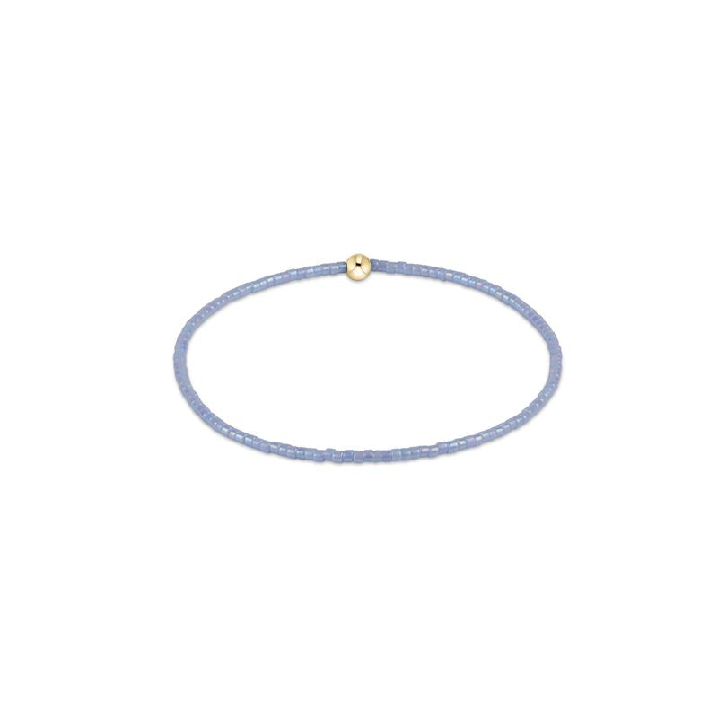 Thin lavender bracelet with a gold bead on a white background