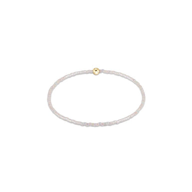 Thin white beaded bracelet with a gold clasp on a white background