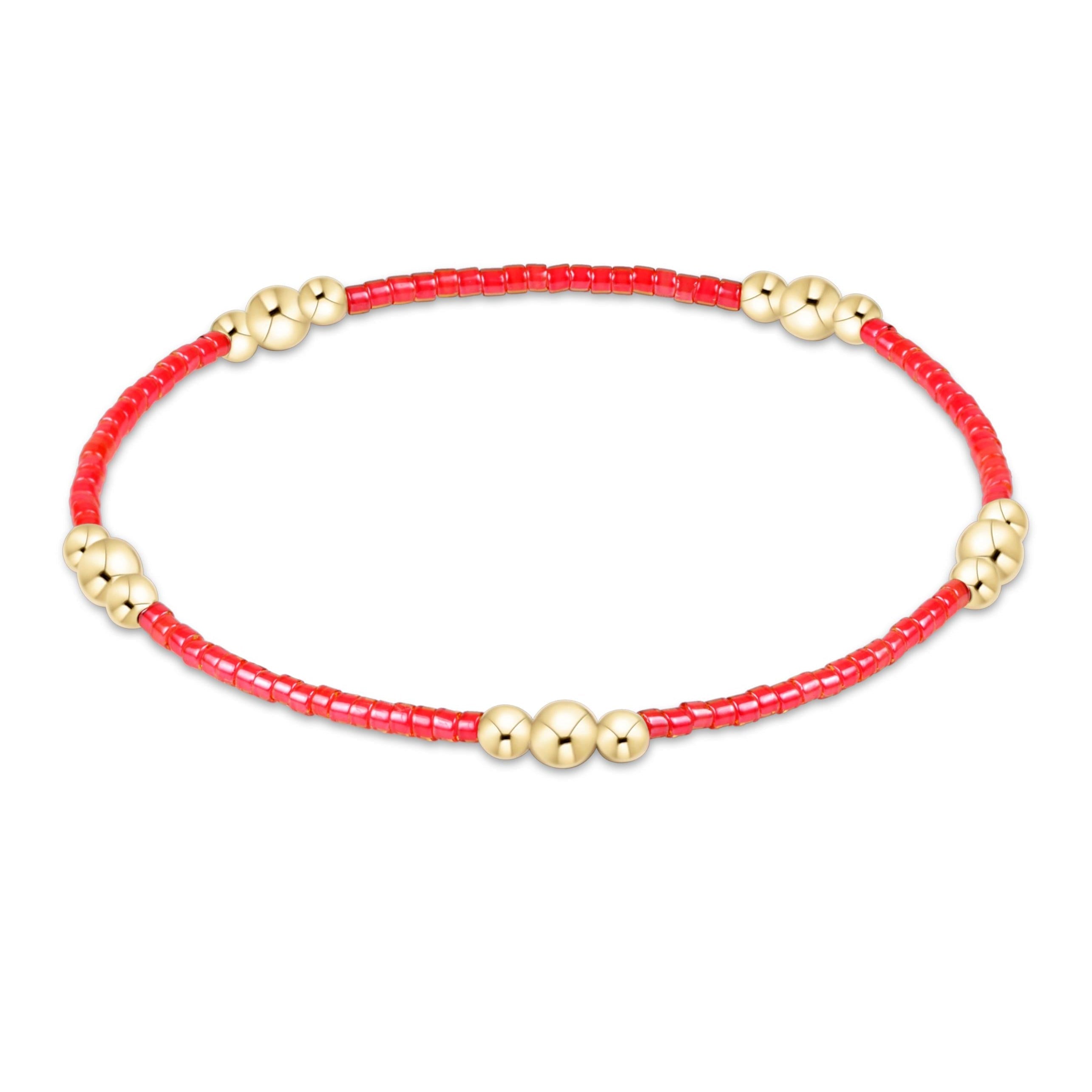 Bracelet with red beads and gold accents on a white background