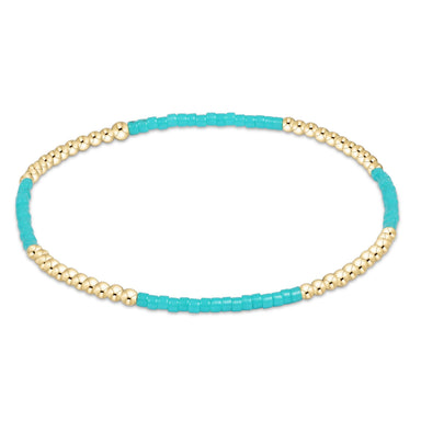 Turquoise and gold beaded bracelet on a white background