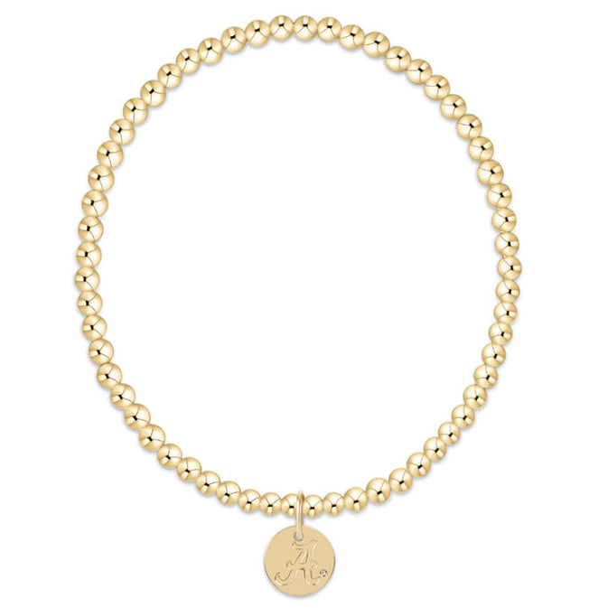 Gold beaded bracelet with a round tag on a white background