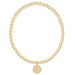 Gold beaded bracelet with a round tag on a white background