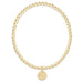 Gold beaded bracelet with a round tag on a white background