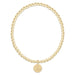 Gold beaded bracelet with a round tag on a white background