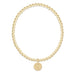 Gold beaded bracelet with a gold charm on a white background