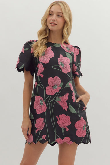 Woman wearing a black dress with pink floral patterns on a white background