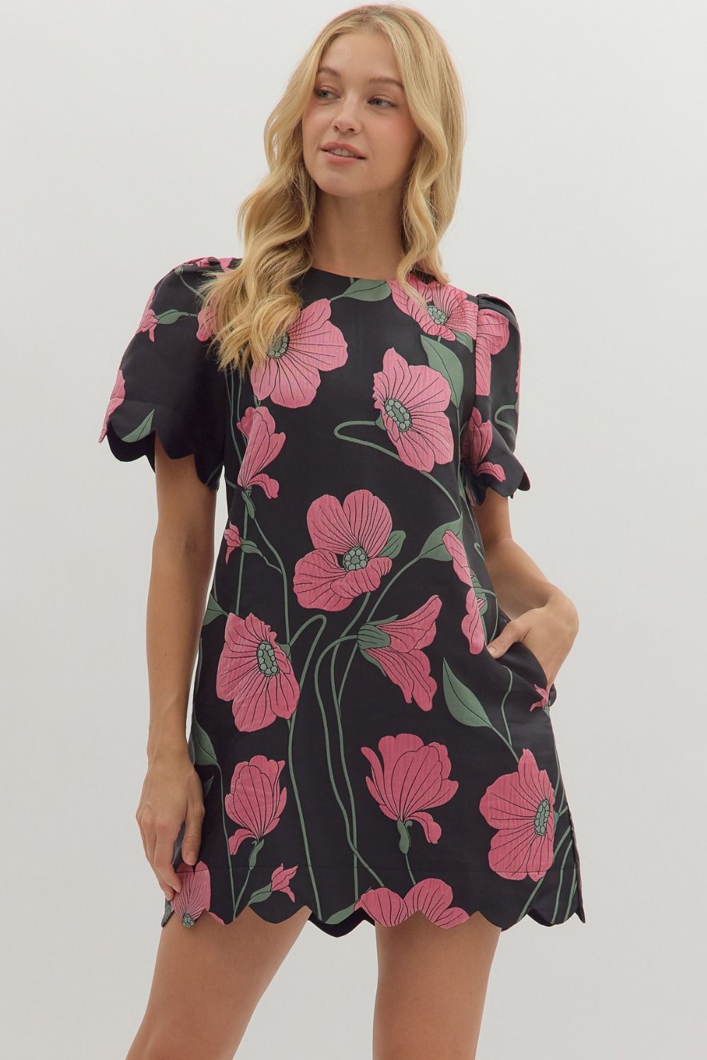 Woman wearing a black dress with pink floral patterns on a white background