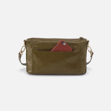 Green leather crossbody bag with a red phone case on a white background