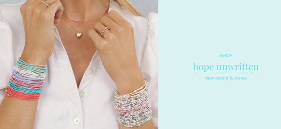 Person wearing colorful e newton bracelets and a necklace with a light blue background and 'hope unwritten' text.
