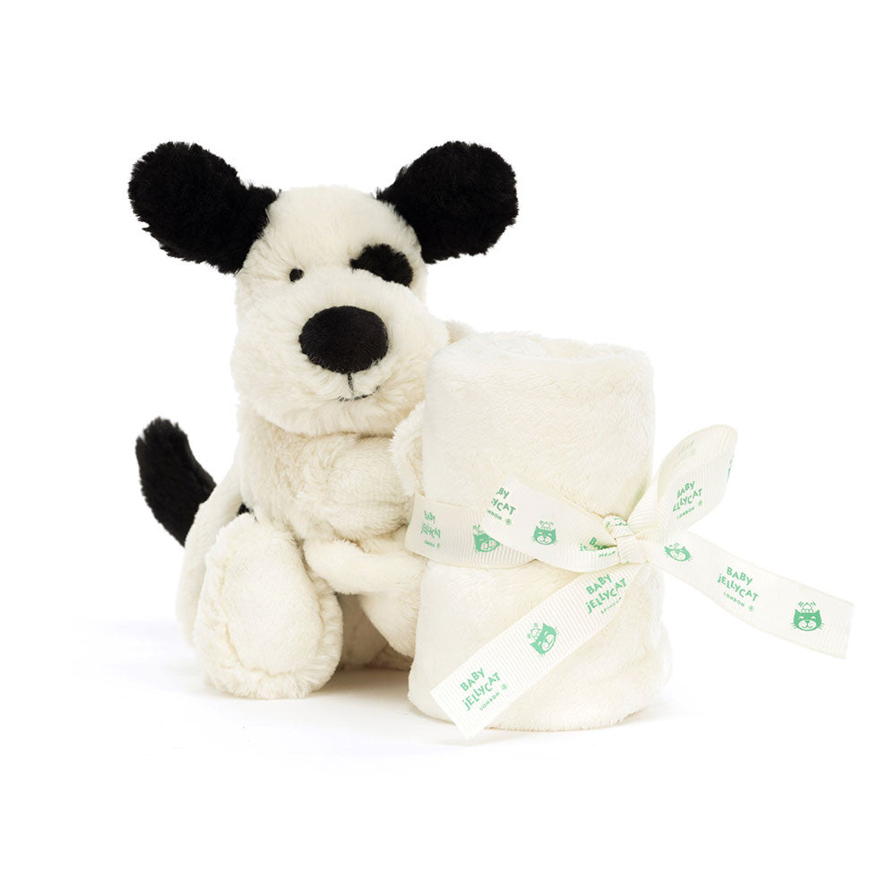 White plush dog toy with black ears and paws, holding a ball of yarn on a white background