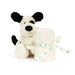 White plush dog toy with black ears and paws, holding a ball of yarn on a white background