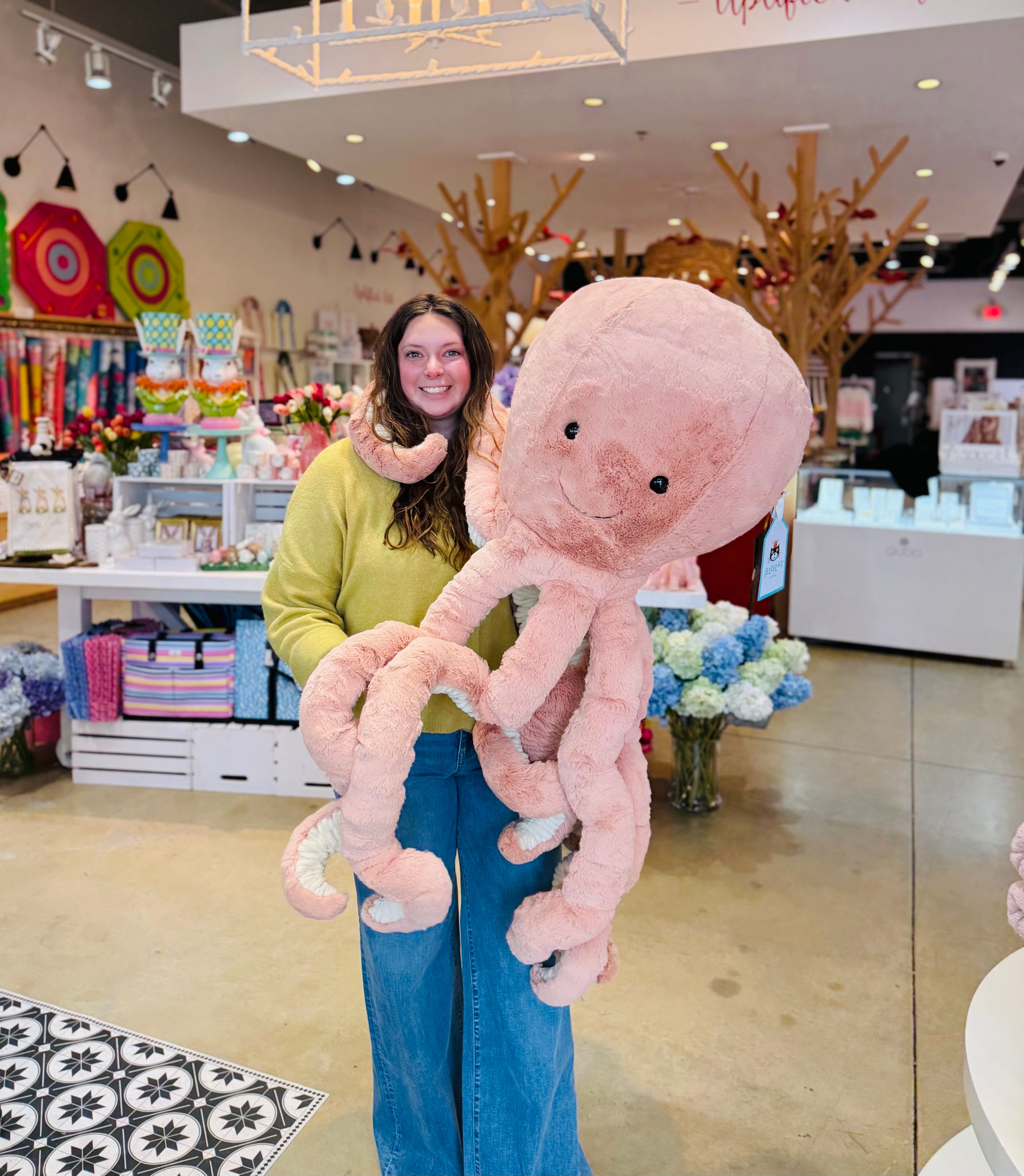 Person holding a large pink plush octopus in a store setting