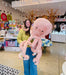 Person holding a large pink plush octopus in a store setting