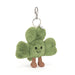 Plush keychain shaped like a green clover with a smiling face on a white background
