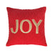 A square-shaped red velvet throw pillow with the word 'JOY' embroidered in gold.