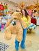 Woman holding a large teddy bear in a store with colorful decorations.