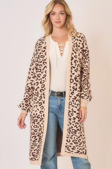 Woman wearing a leopard print cardigan over a white top and blue jeans on a plain background