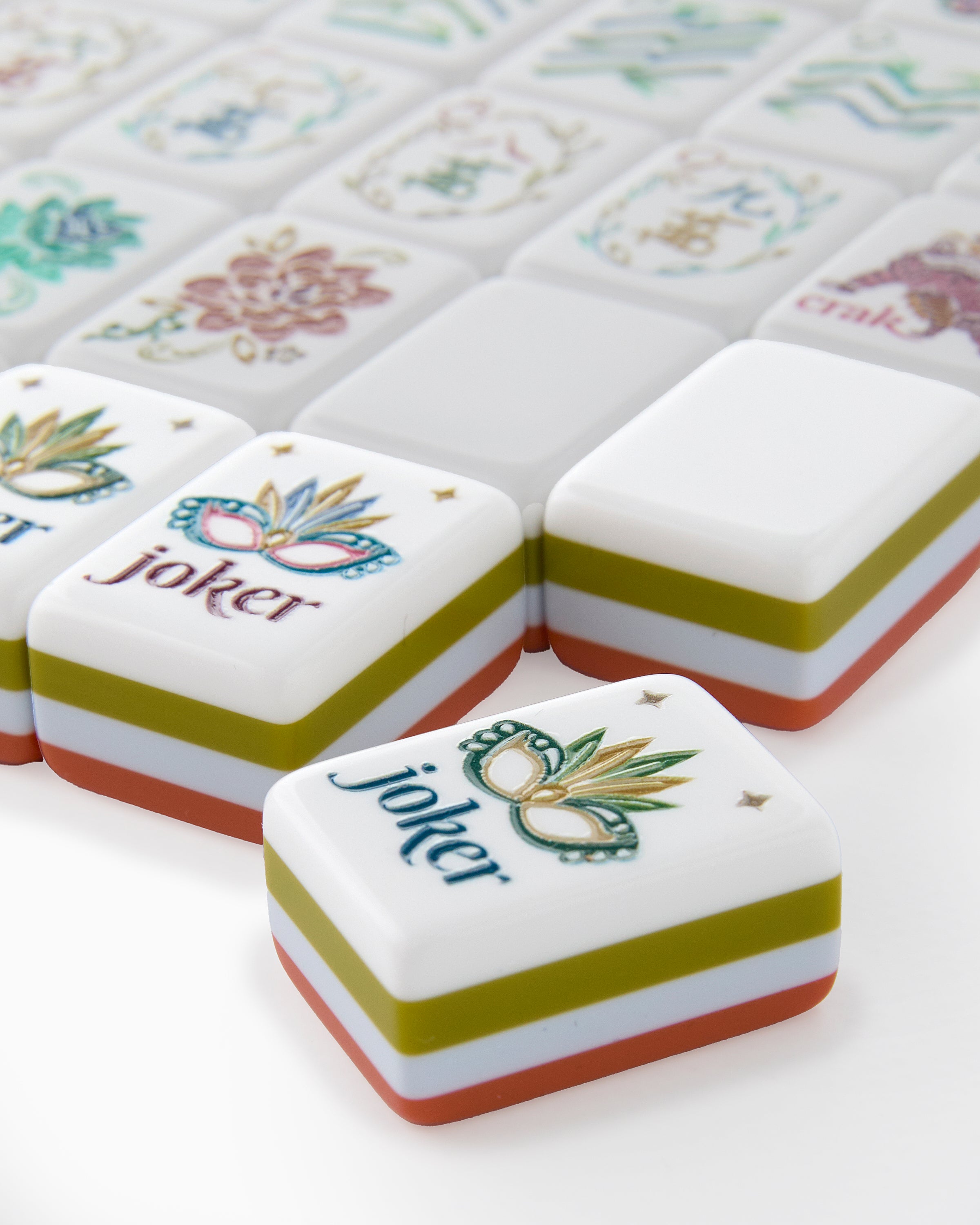 Close-up of decorative tiles with 'joker' and floral designs on a white surface.