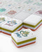 Close-up of decorative tiles with 'joker' and floral designs on a white surface.