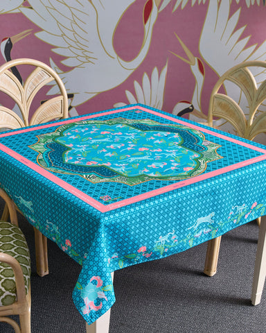 Tablecloth with floral design on a table against a pink wall with bird patterns