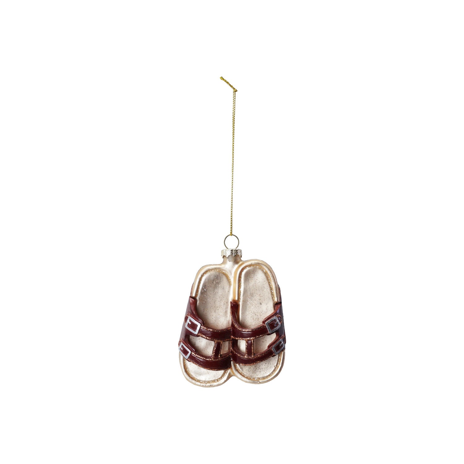 A glass ornament in the shape of a pair of sandals, with brown straps and gold-colored metal hardware, hanging from a gold-colored string.