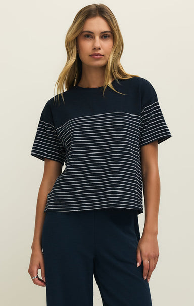 Woman wearing a navy blue and white striped shirt against a plain background