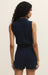 Woman wearing a navy blue sleeveless romper against a beige background
