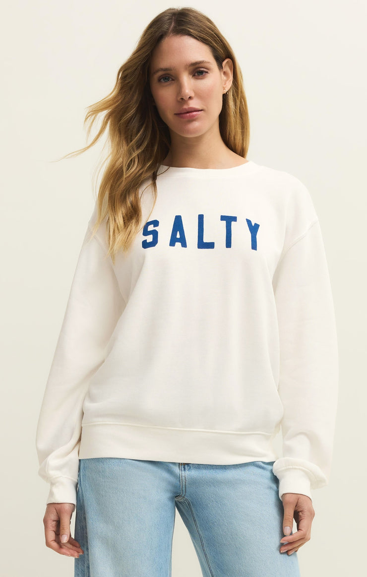 Woman wearing a white sweatshirt with 'SALTY' text on a plain background