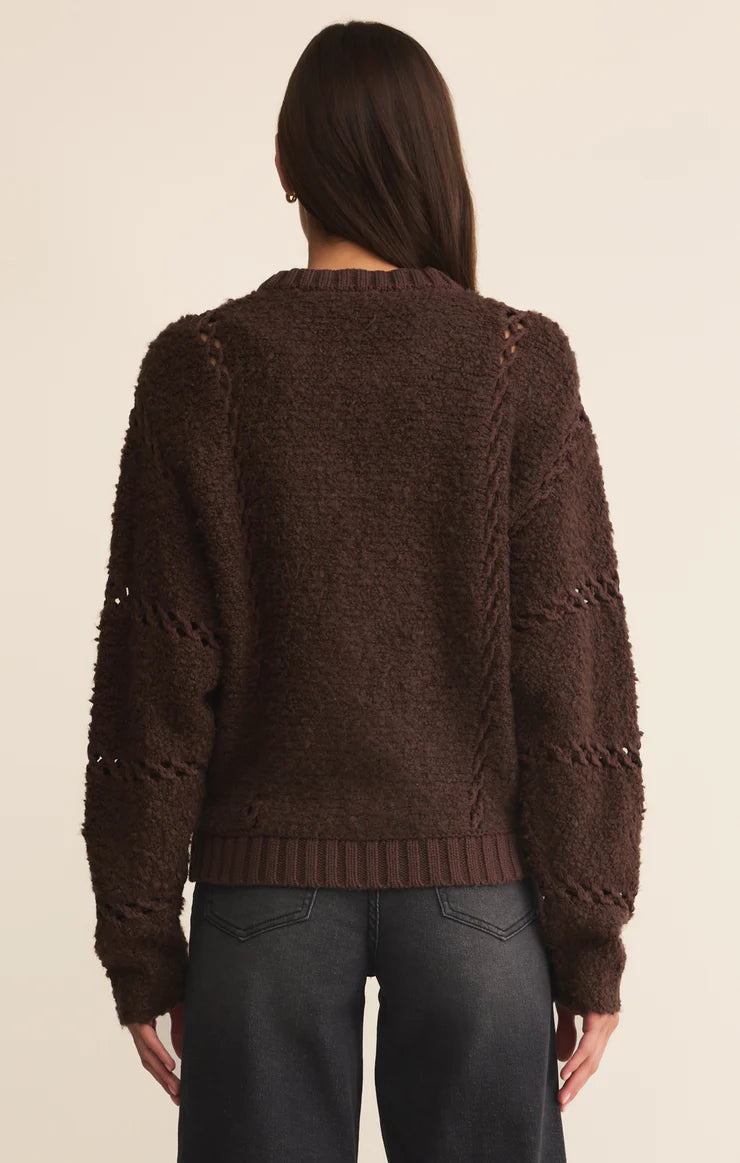 Person wearing a brown knitted sweater on a beige background