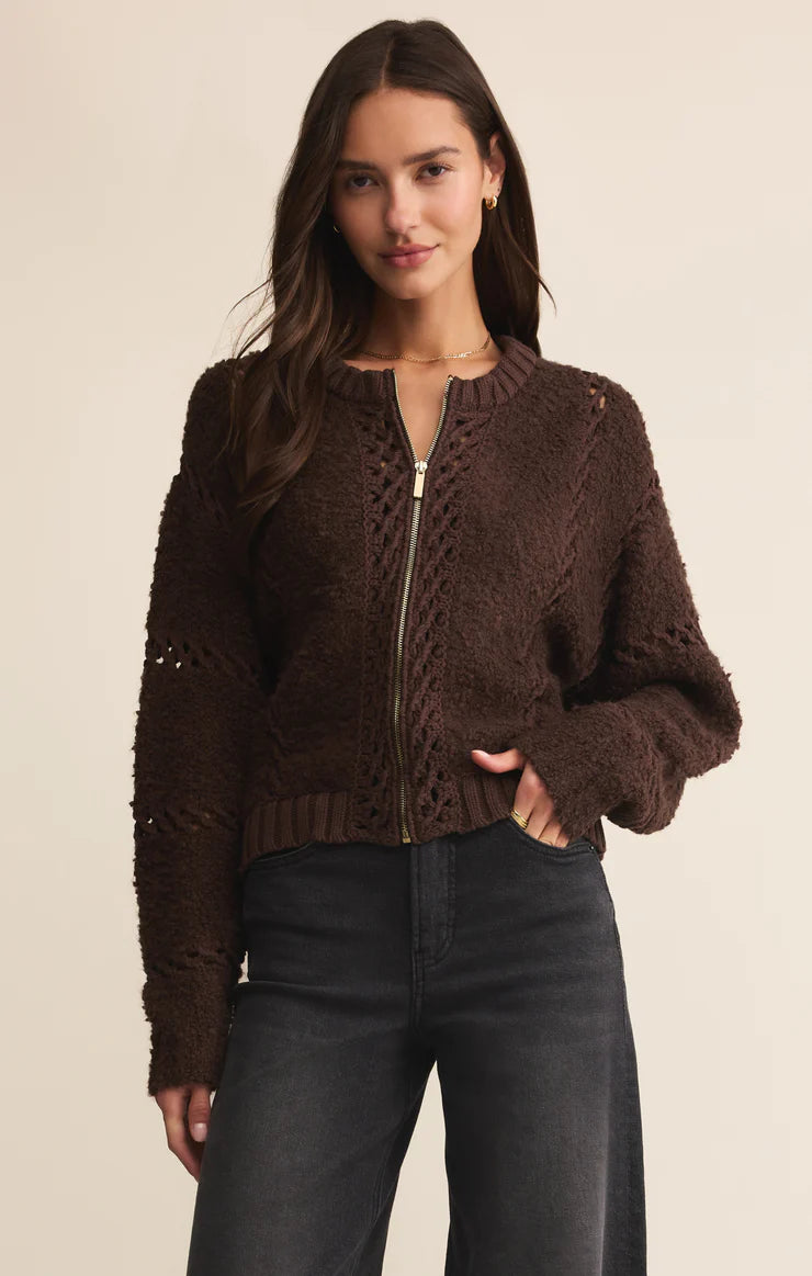 Woman wearing a brown knitted cardigan with a zipper on a beige background