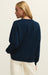 Person wearing a navy blue sweater on a beige background