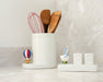 White container with kitchen utensils on a light surface