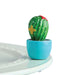A hand-painted ceramic cactus mini figurine in green, red, and white colors, designed to sit in a dishwasher-safe base piece.